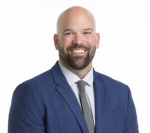 Professional portrait of Josh "JD" Dillender in a blue suit and gray tie.