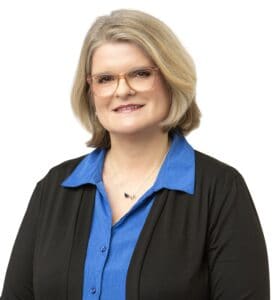 Professional portrait of Michele Hamilton wearing glasses and a blue blouse.