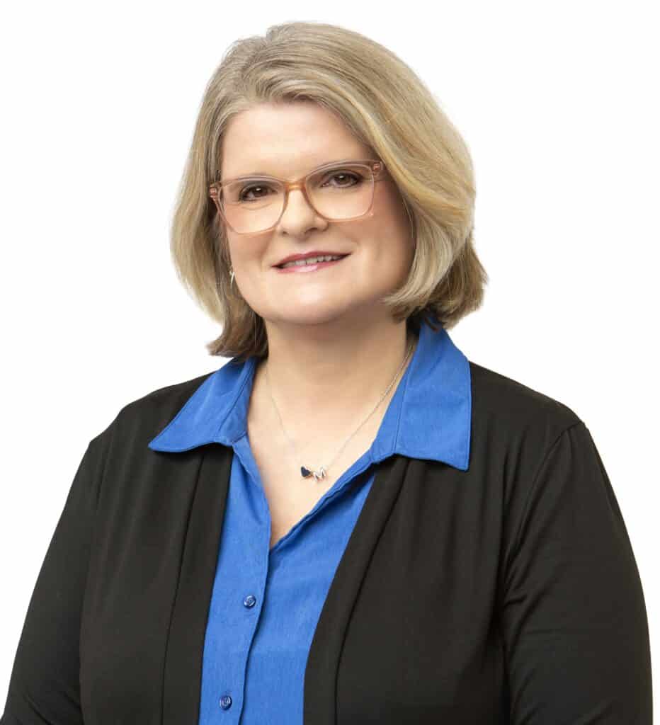 Professional portrait of Michele Hamilton wearing glasses and a blue blouse.